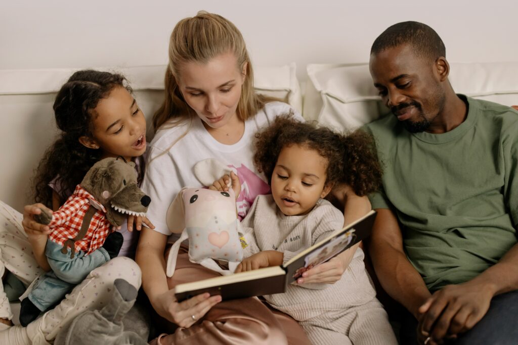 Deux enfants lisent un livre de souvenirs avec leurs parents. 